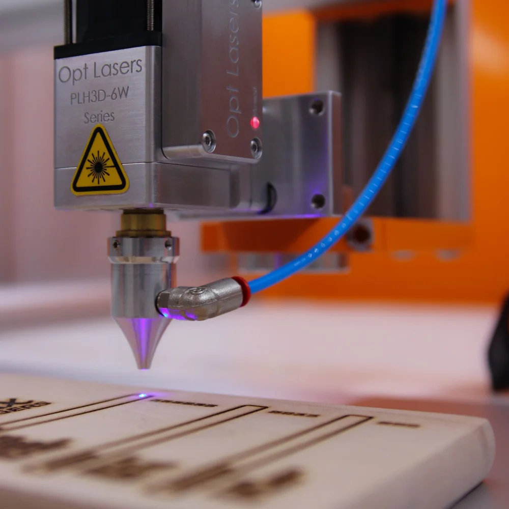 Close-up of a laser engraving head marking a flat sheet