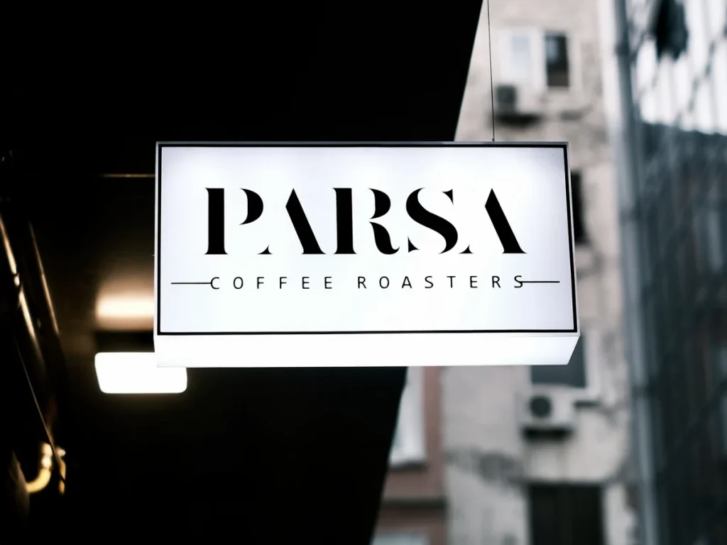 A lit projecting light box sign on a building wall at dusk