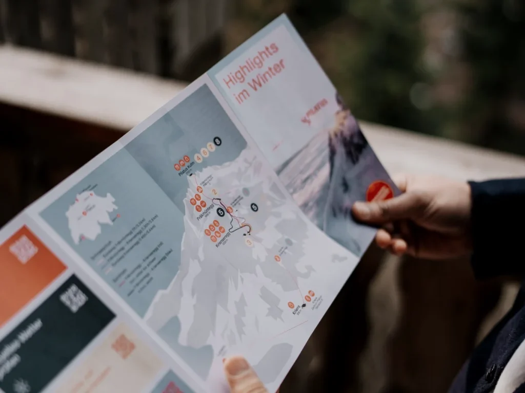 An open printed brochure being read, held in both hands